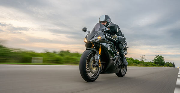 Black sport bike racing down road with scenery blurred - mobile optimized