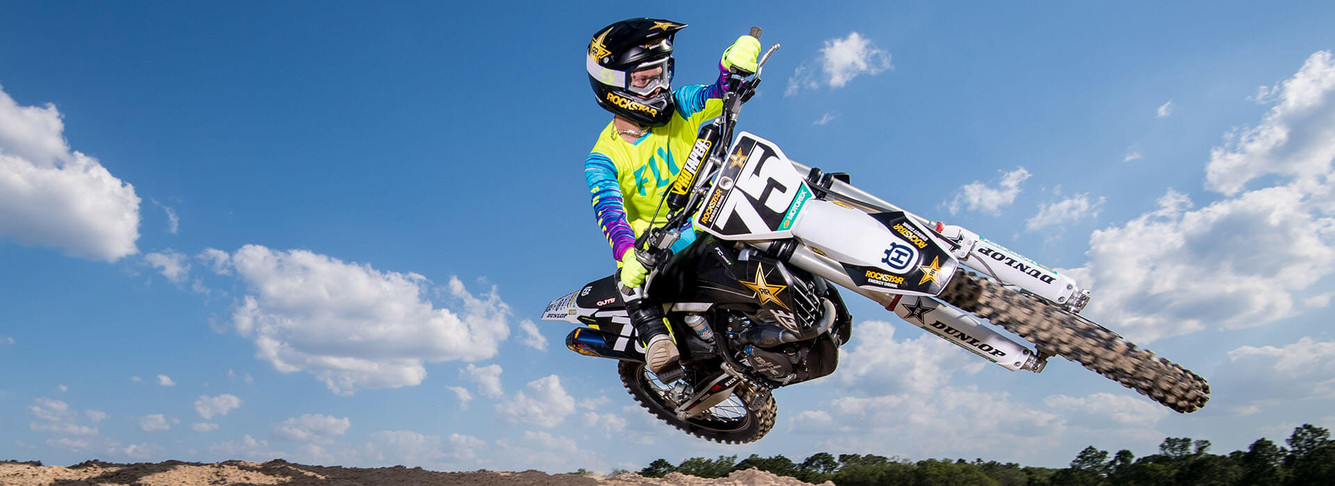 White Husqvarna dirt bike doing a table top jump